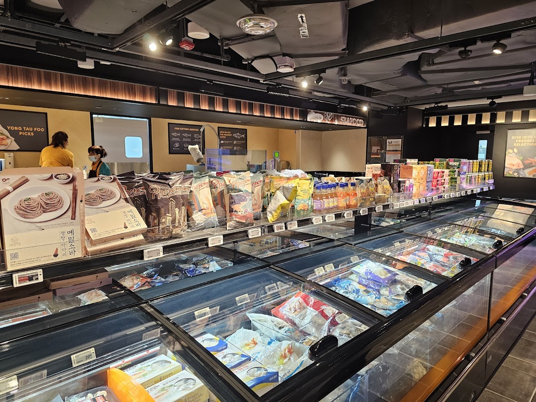 An interior view of FairPrice Finest, showcasing frozen food aisles, packaged goods, and staff at service counters.