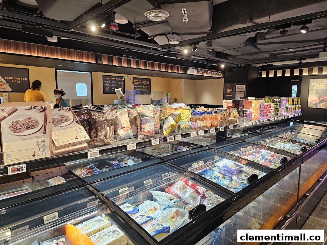 An interior view of FairPrice Finest, showcasing frozen food aisles, packaged goods, and staff at service counters.