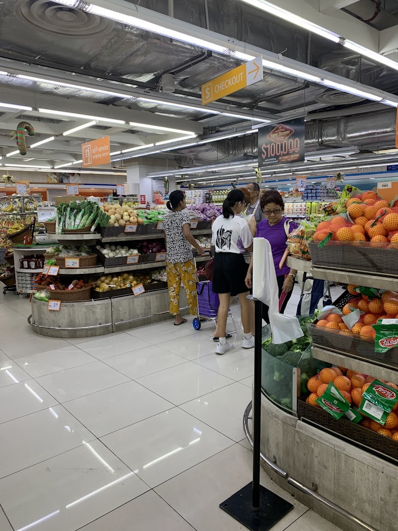 Shoppers browse fresh produce in a brightly lit FairPrice Finest supermarket aisle.