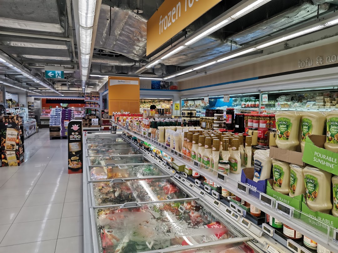 A well-stocked aisle at FairPrice Finest supermarket, featuring frozen food freezers and shelves of various grocery items.