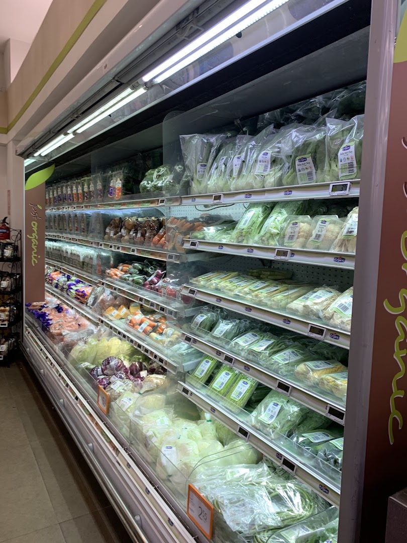 A refrigerated display case filled with various packaged fresh vegetables and organic produce.