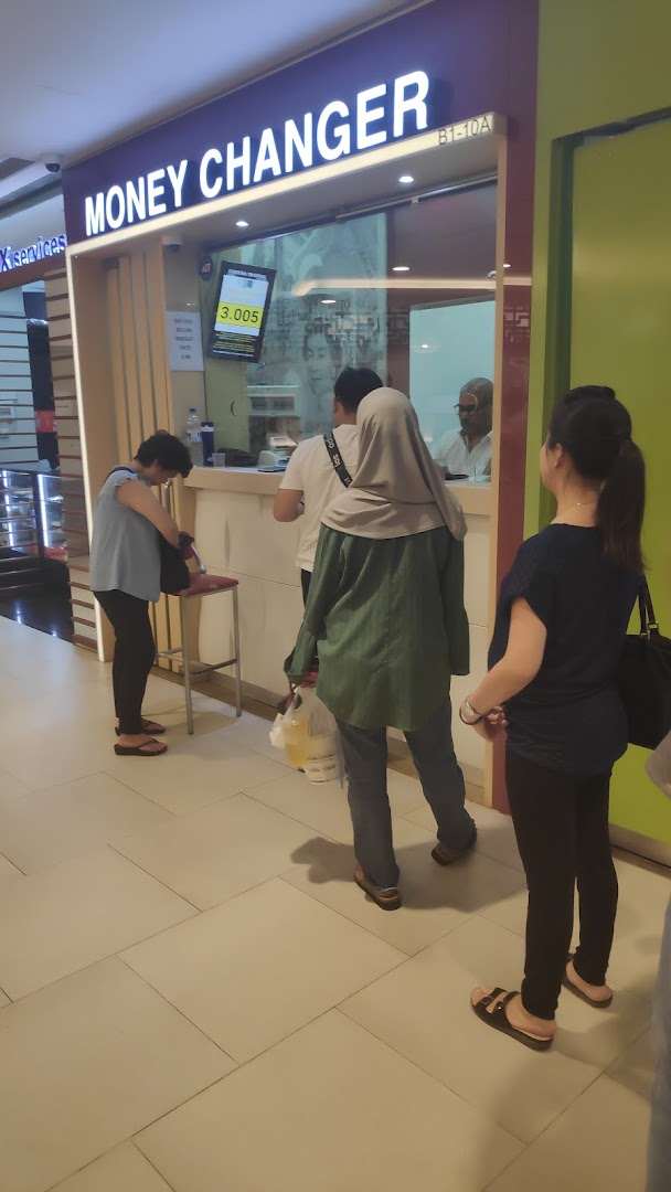 Customers queueing at the counter of Faizura Trading Clementi Money Changer, showing current exchange rates.