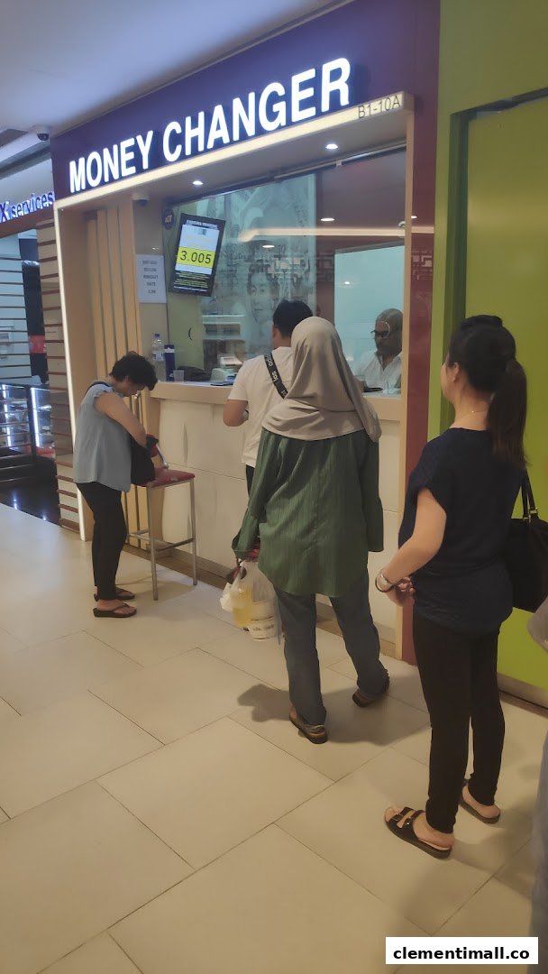 Customers queueing at the counter of Faizura Trading Clementi Money Changer, showing current exchange rates.