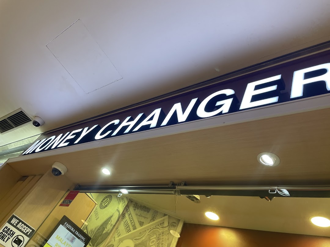 Close-up of the illuminated 'MONEY CHANGER' sign above the shop entrance.