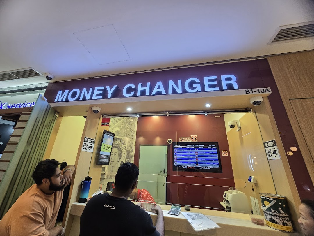 Interior view of Faizura Trading Money Changer with customers at the counter.