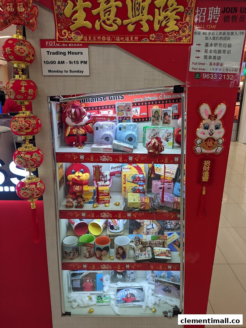 A retail display case featuring instant cameras, photo films, personalized gifts, and photo printing services, with shop hours.