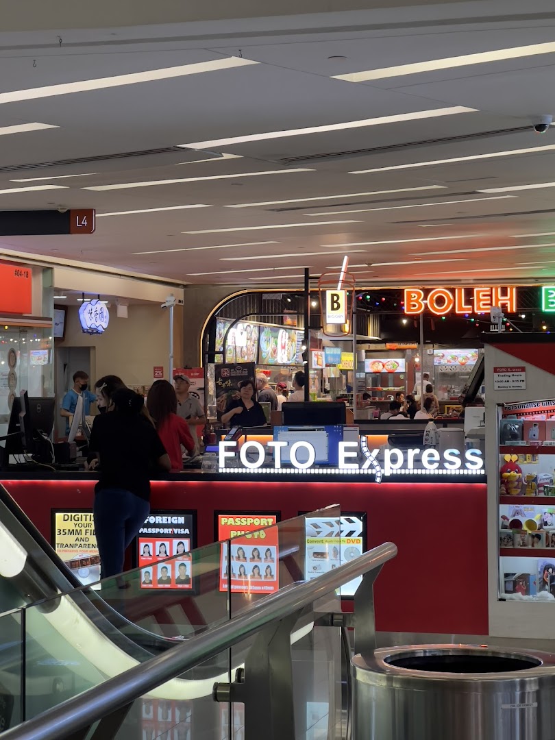 Customers at the Foto Express counter, offering photo printing, passport photos, and digitization services.