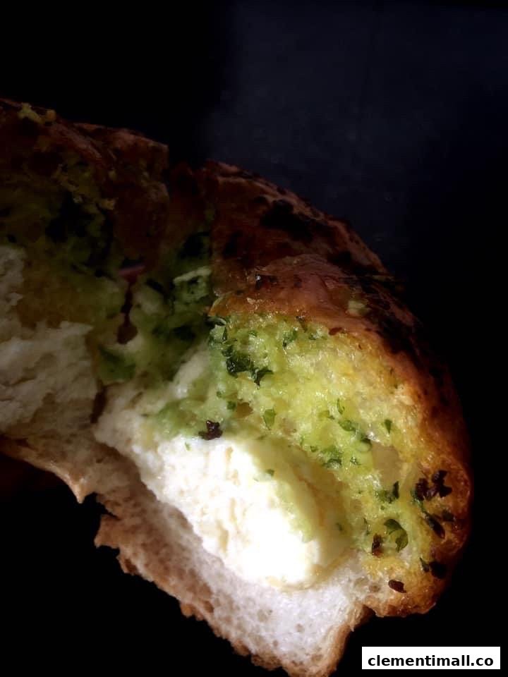 A close-up of a savory bread with a creamy filling and green herbs, showing a bite taken.