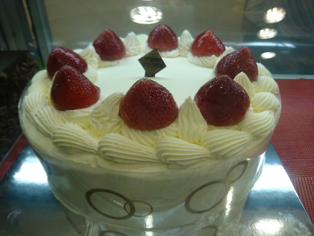 A delicious white cake topped with fresh strawberries and whipped cream, displayed in a bakery case.