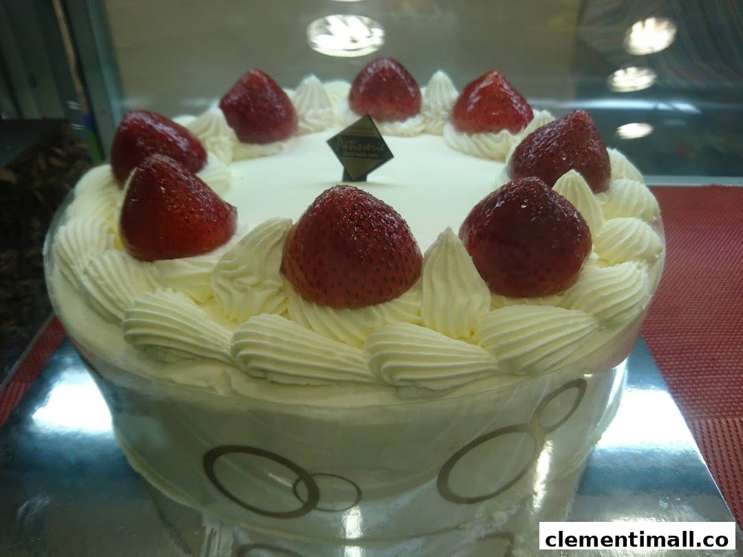A delicious white cake topped with fresh strawberries and whipped cream, displayed in a bakery case.