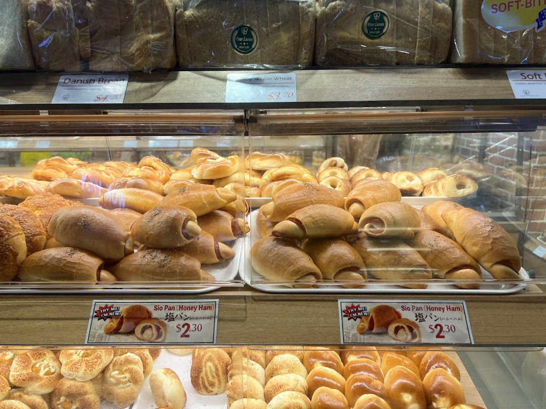 A vibrant display case showcasing a variety of freshly baked breads and pastries at Four Leaves bakery.
