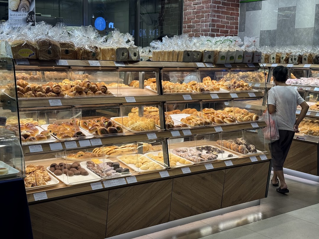 A bakery interior showcasing diverse fresh bread and pastries in display cases, with a customer browsing.