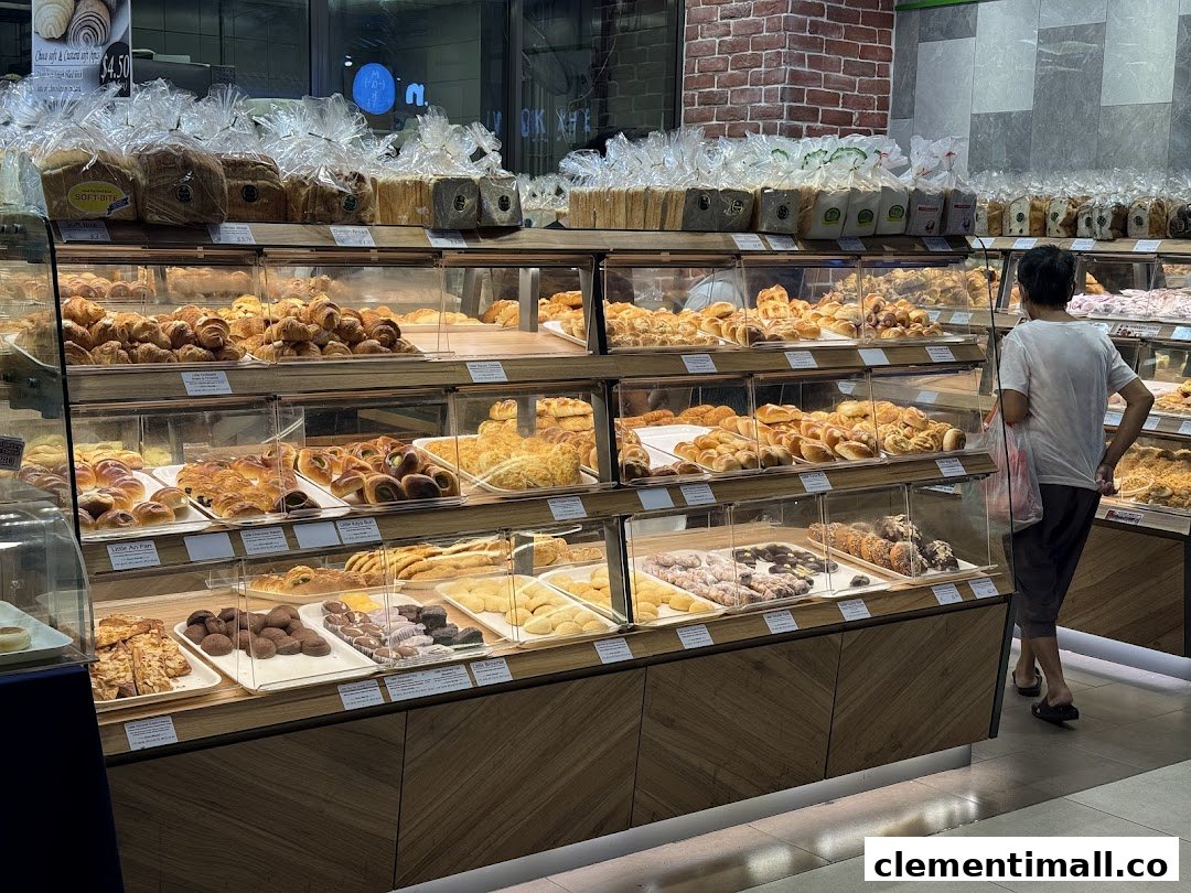 A bakery interior showcasing diverse fresh bread and pastries in display cases, with a customer browsing.