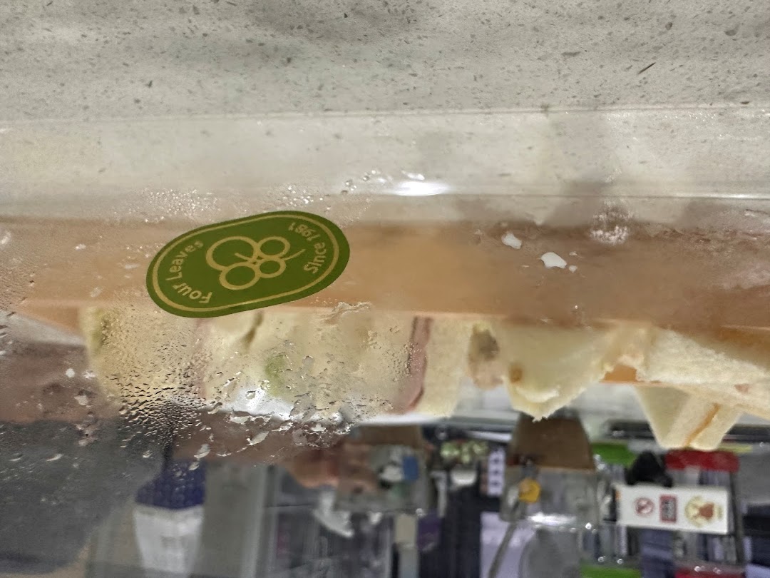 Close-up of fresh sandwiches displayed in a refrigerated case, featuring the Four Leaves logo.