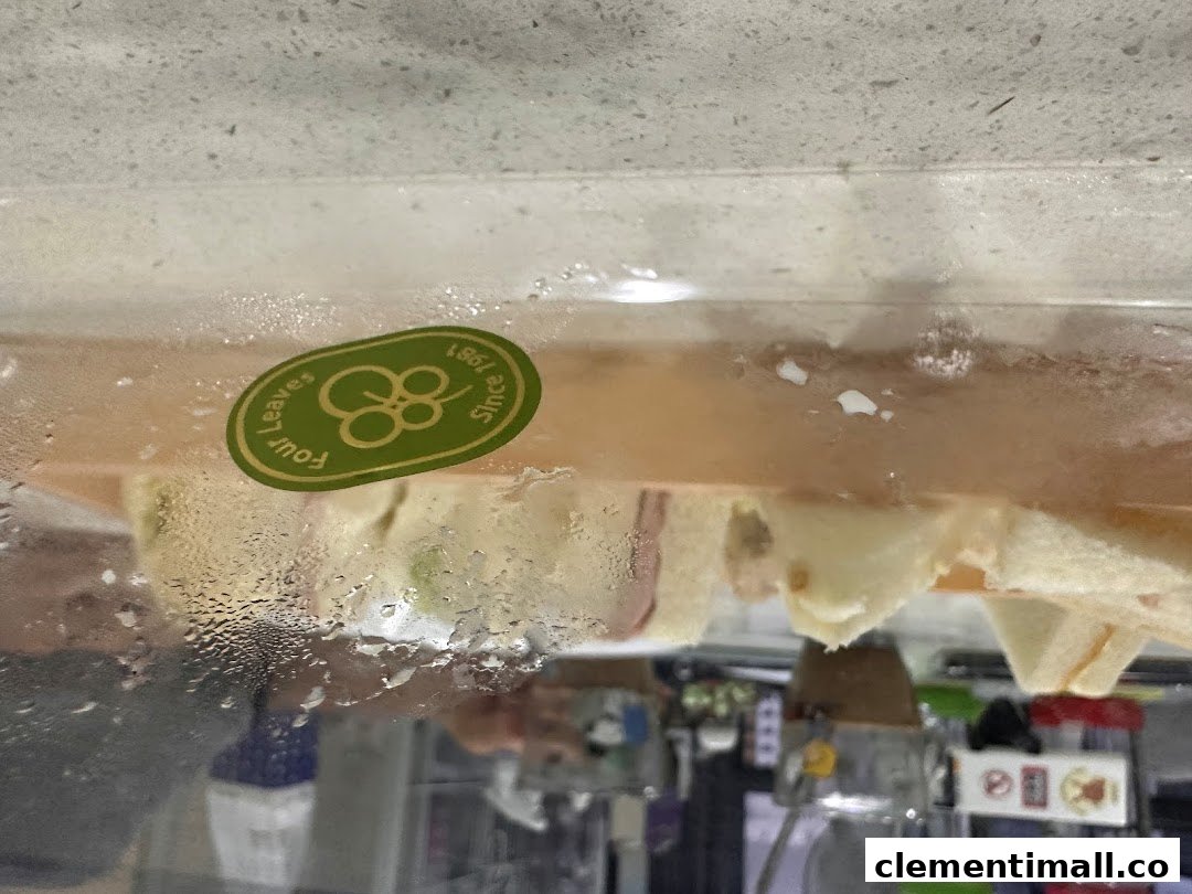 Close-up of fresh sandwiches displayed in a refrigerated case, featuring the Four Leaves logo.