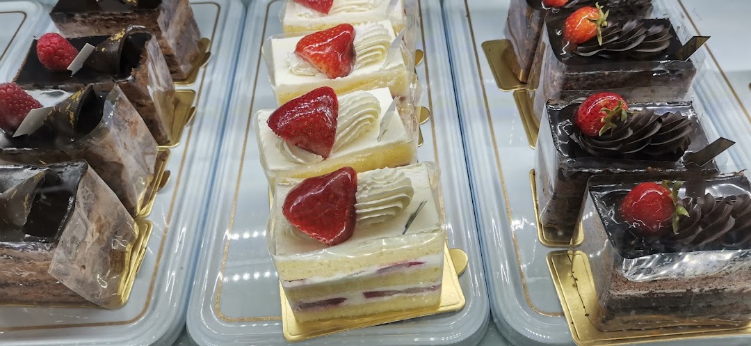 Rows of delicious chocolate and strawberry cakes displayed in a bakery showcase.