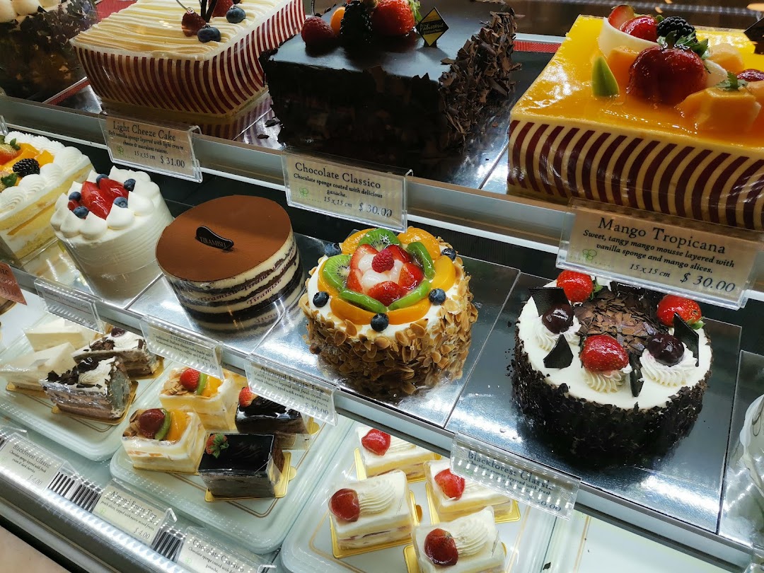 A vibrant display of various cakes and pastries in a bakery showcase.