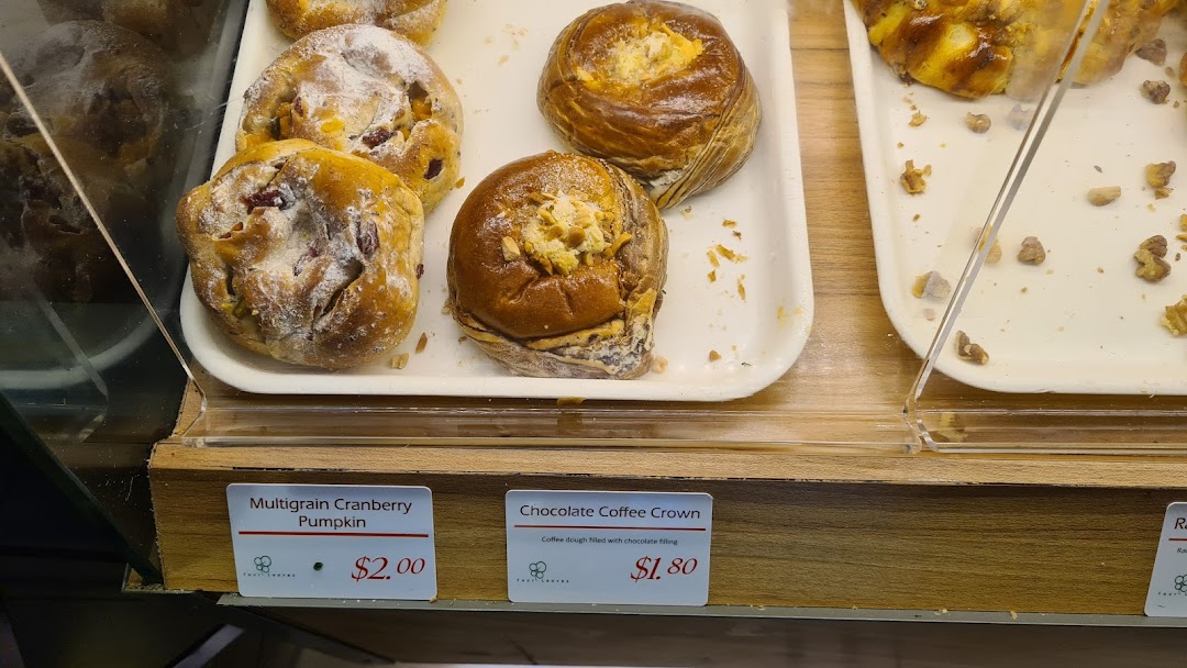 Close-up of freshly baked pastries and breads in a display case with price tags.