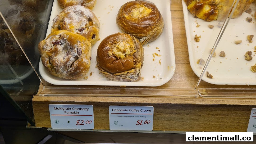 Close-up of freshly baked pastries and breads in a display case with price tags.