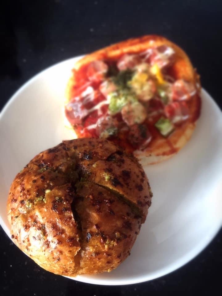 A plate featuring a savory garlic bread bun and a mini pizza bun from Four Leaves.