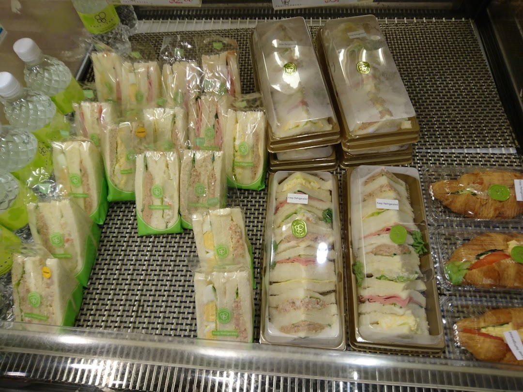 A display case filled with various pre-packaged sandwiches, including triangle-cut and long-cut, and croissants.
