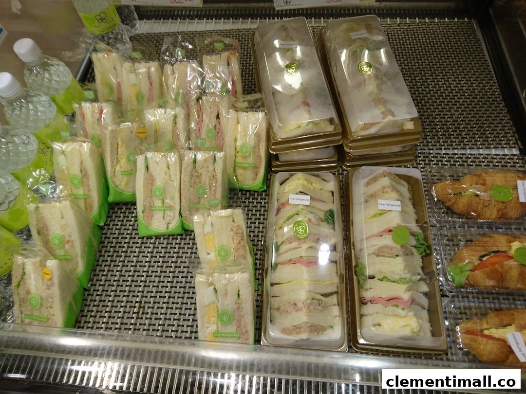 A display case filled with various pre-packaged sandwiches, including triangle-cut and long-cut, and croissants.