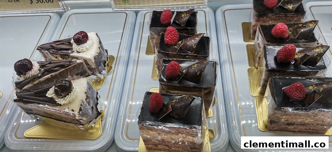 A vibrant display of chocolate and cream cakes, some topped with raspberries and cherries.