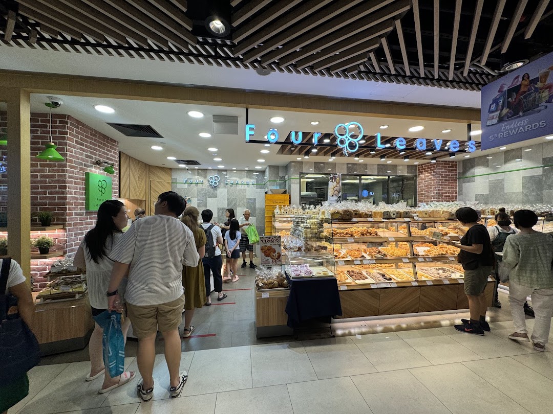 Customers queue at the entrance of Four Leaves bakery, showcasing a wide selection of freshly baked goods.