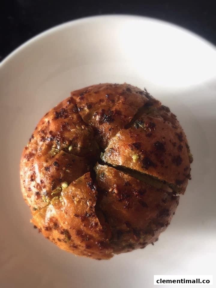 A close-up of a golden-brown, savory bread or bun, possibly garlic bread, served in a white bowl.