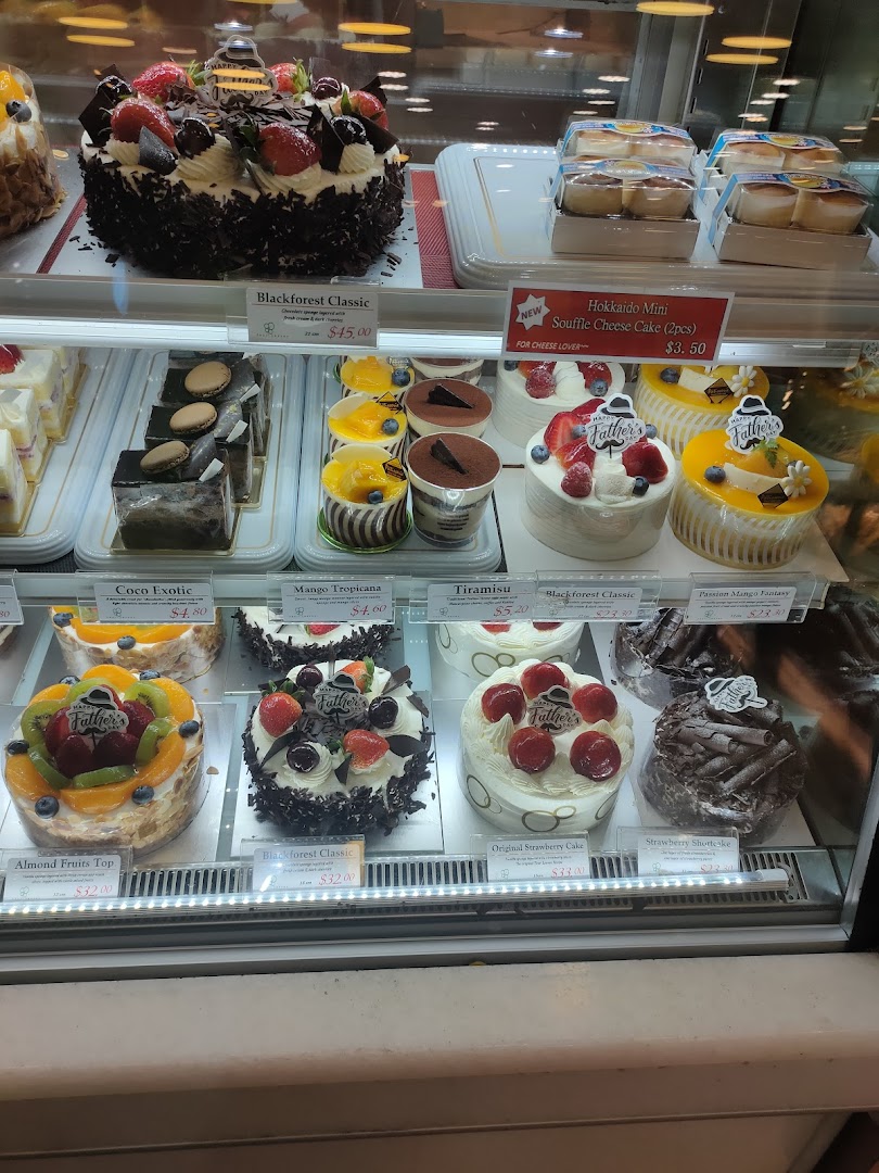 A vibrant display case showcasing a variety of delicious cakes and pastries, including Blackforest and fruit tarts.