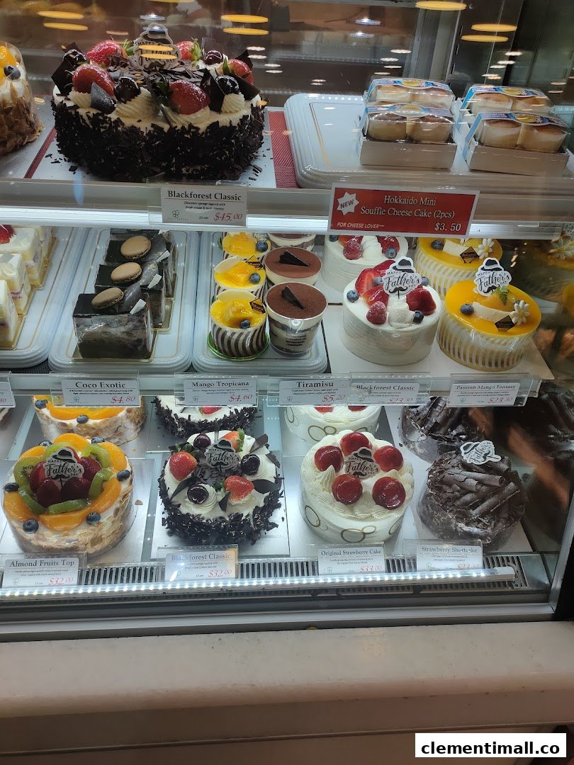 A vibrant display case showcasing a variety of delicious cakes and pastries, including Blackforest and fruit tarts.