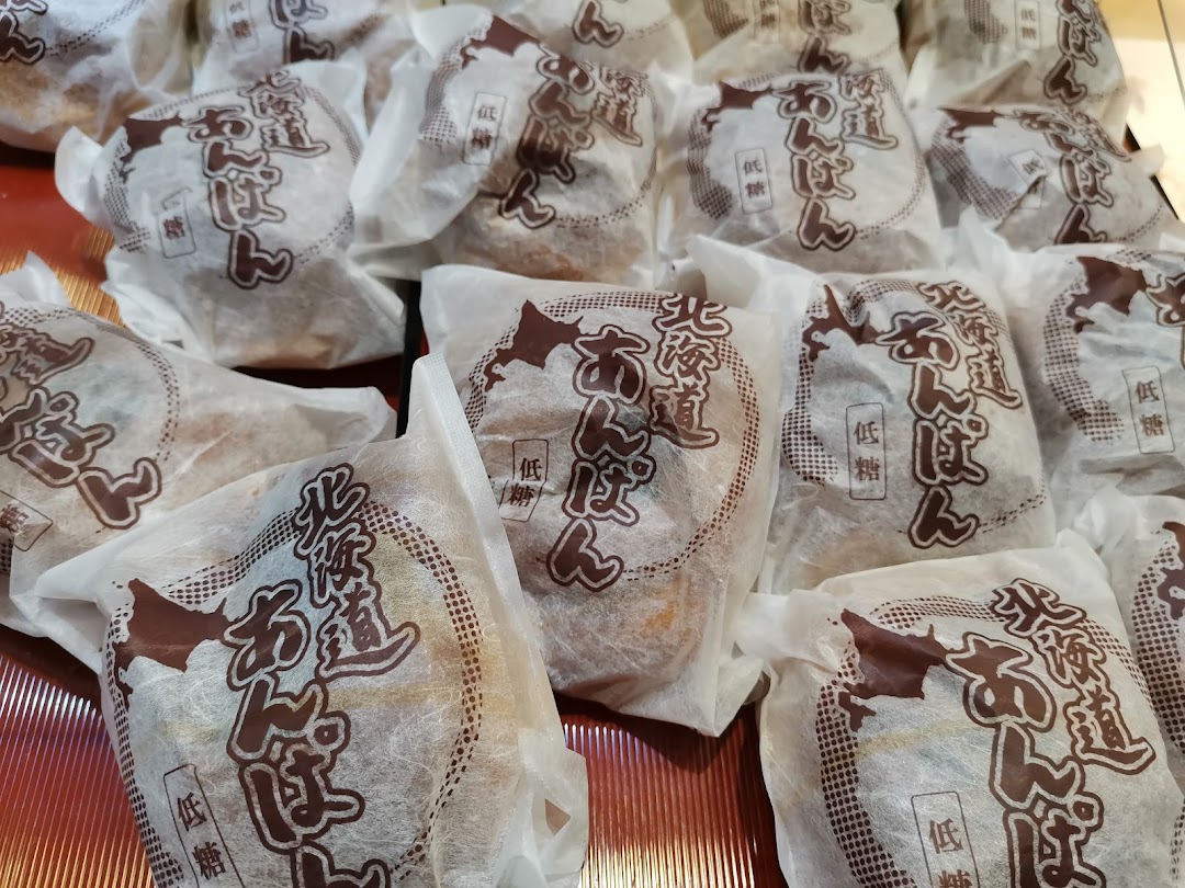 Close-up of numerous individually wrapped Japanese bean paste buns (anpan) on display.