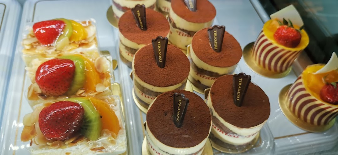 A vibrant display of individual tiramisu cups, fruit tarts, and other delightful pastries in a dessert case.