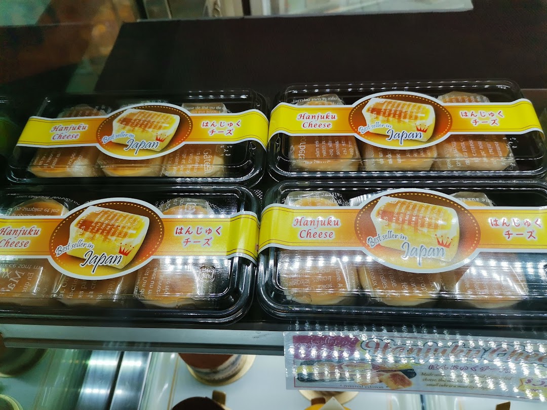 Close-up of multiple packages of 'Hanjuku Cheese' cakes displayed in a retail bakery case.