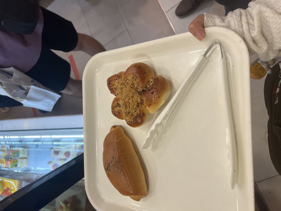 A customer holds a tray with freshly baked buns and tongs from Four Leaves bakery.