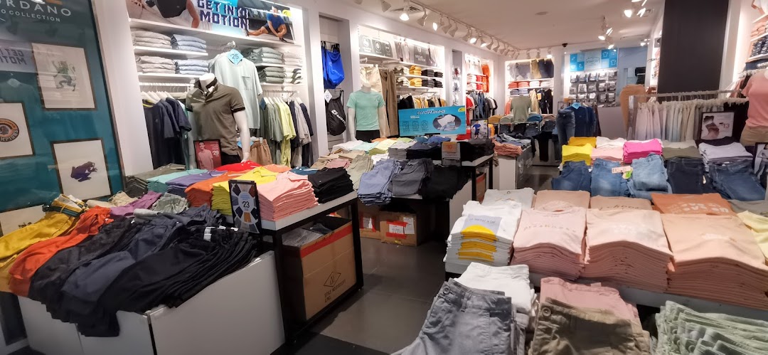 Interior view of a Giordano clothing store, showcasing neatly arranged casual wear, folded apparel, and mannequins.