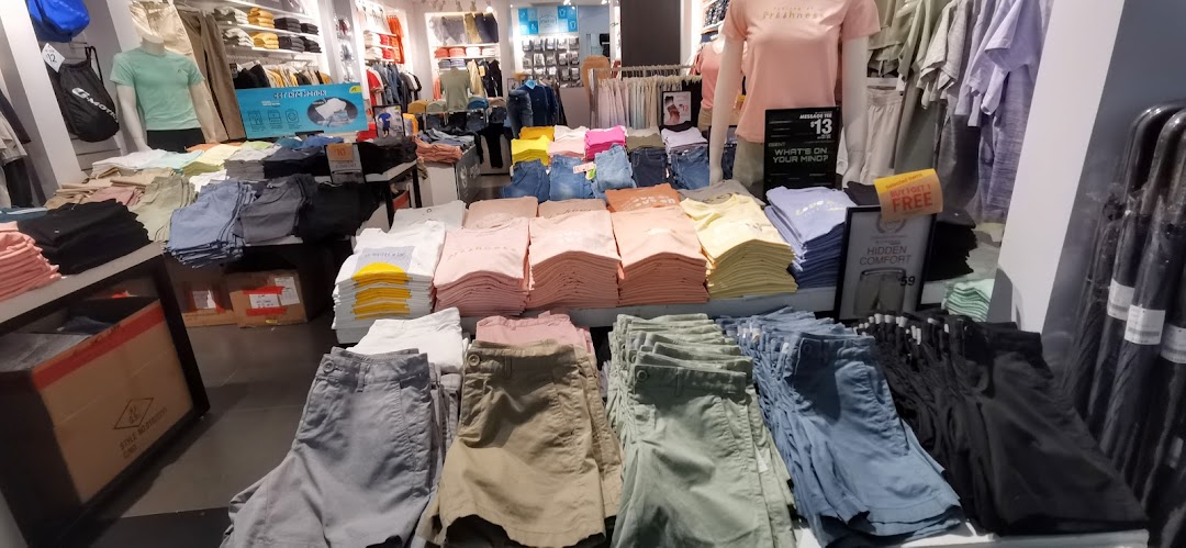 An interior view of Giordano, showcasing neatly folded casual wear, including t-shirts and shorts, with mannequins.