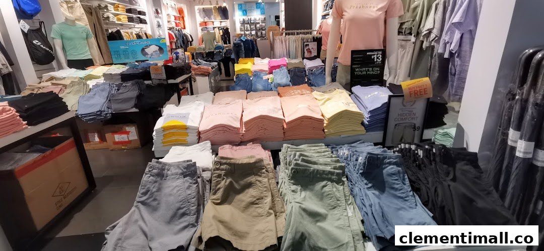 An interior view of Giordano, showcasing neatly folded casual wear, including t-shirts and shorts, with mannequins.