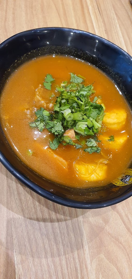 A vibrant bowl of mala tang soup with fresh herbs and various ingredients.