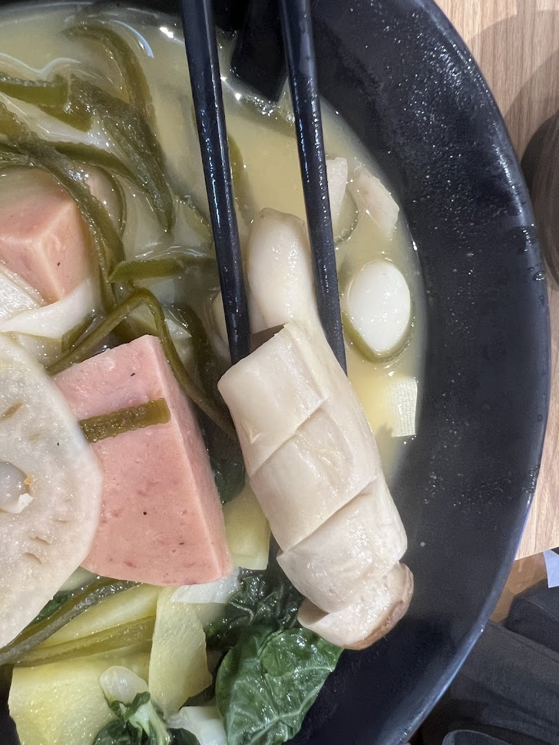 A close-up of a bowl of Mala Tang with various ingredients like mushrooms, lotus root, and luncheon meat.