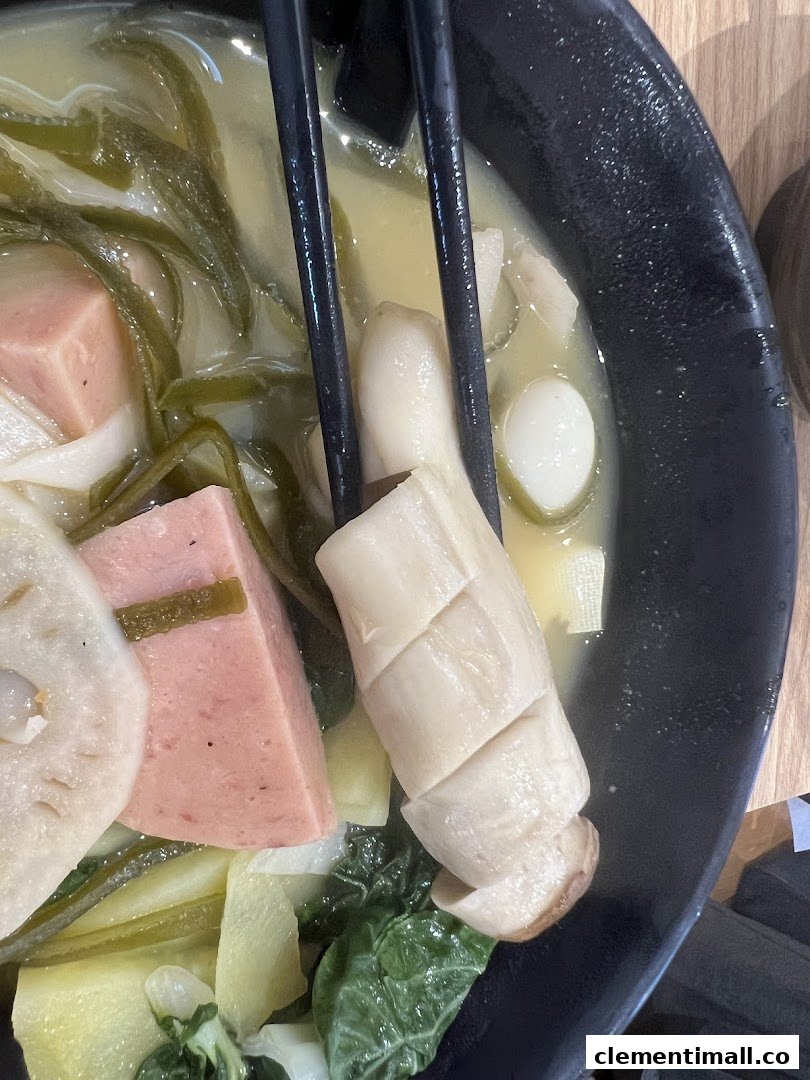A close-up of a bowl of Mala Tang with various ingredients like mushrooms, lotus root, and luncheon meat.