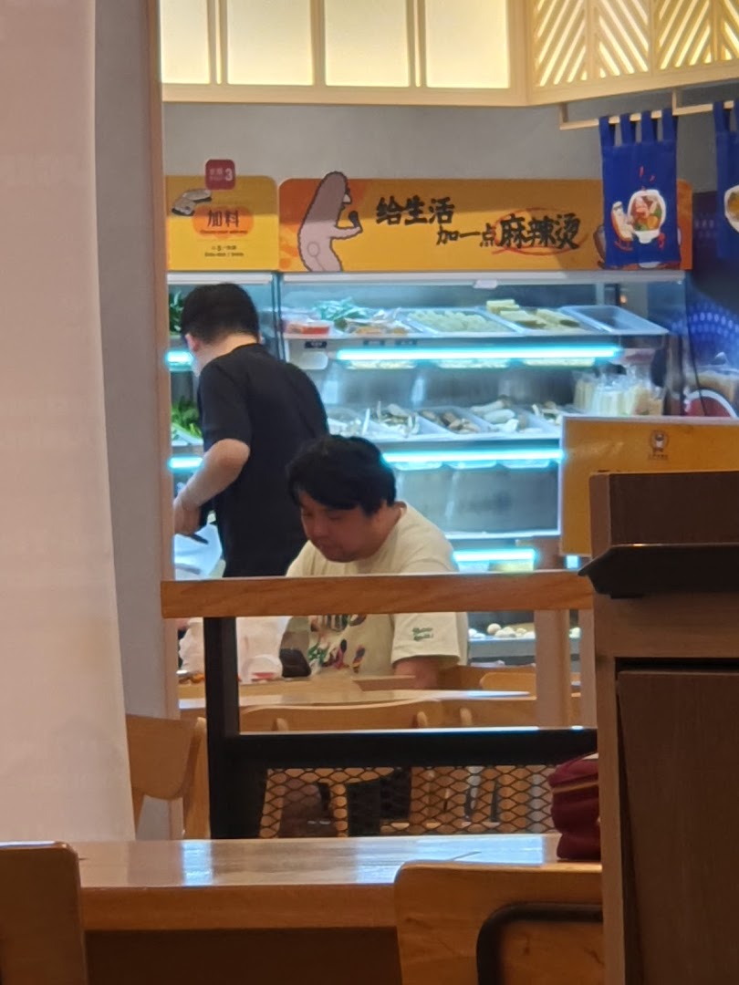 Diners and staff interact near the fresh ingredient display at Gong Yuan Ma La Tang.