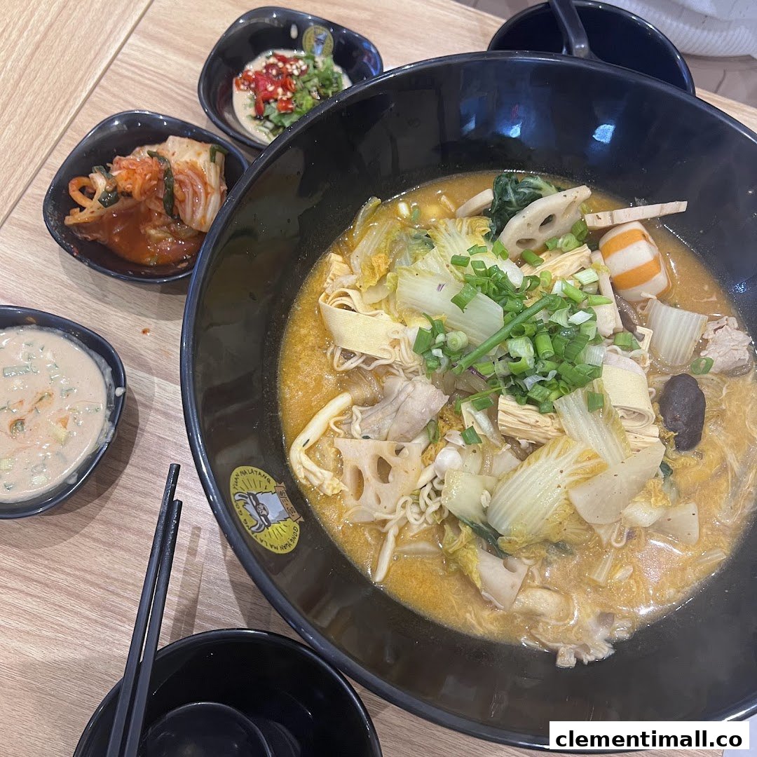 A vibrant bowl of Mala Tang with assorted ingredients and accompanying side dishes on a wooden table.