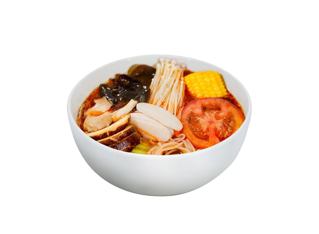 A vibrant bowl of Ma La Tang featuring various ingredients like mushrooms, corn, tomato, and noodles.