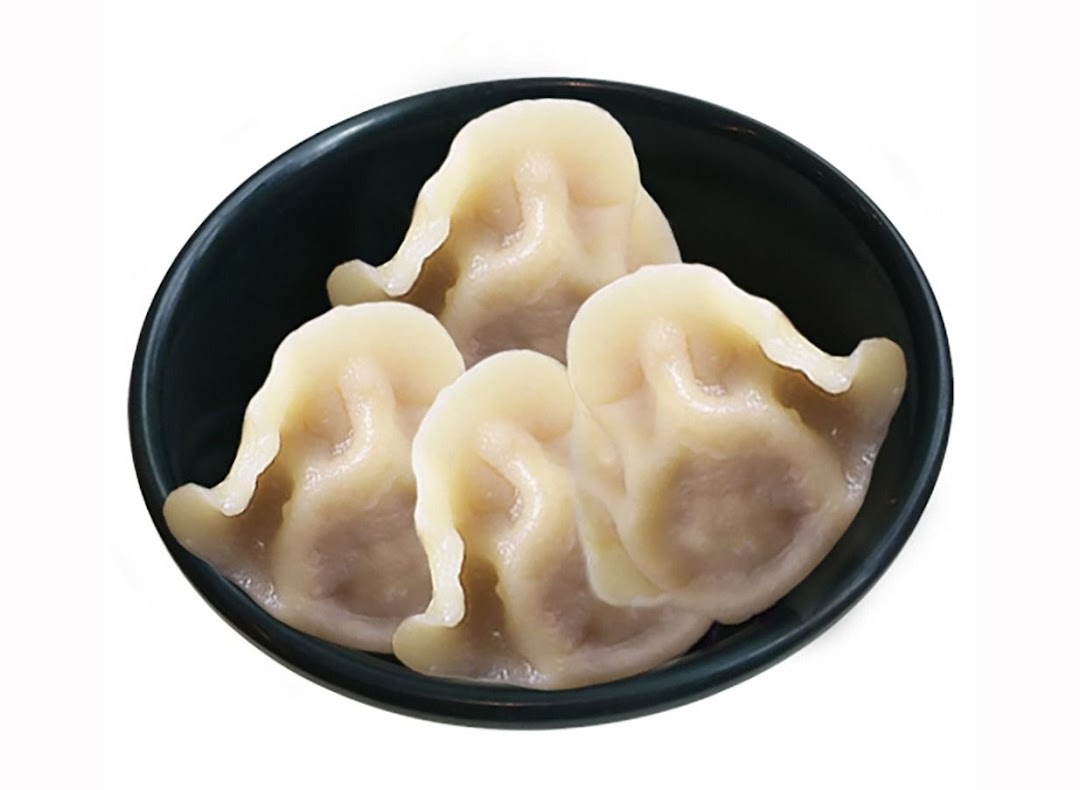 A dark bowl filled with several plump, steamed dumplings, showcasing a popular side dish.