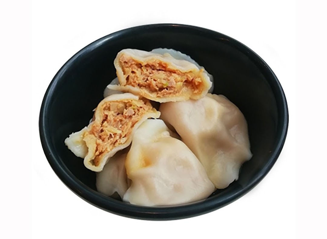A bowl of savory dumplings, with one cut open to reveal the delicious filling.