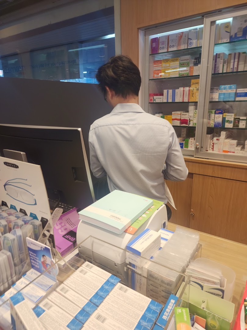 A staff member assists at the Guardian pharmacy counter, surrounded by health and beauty products.