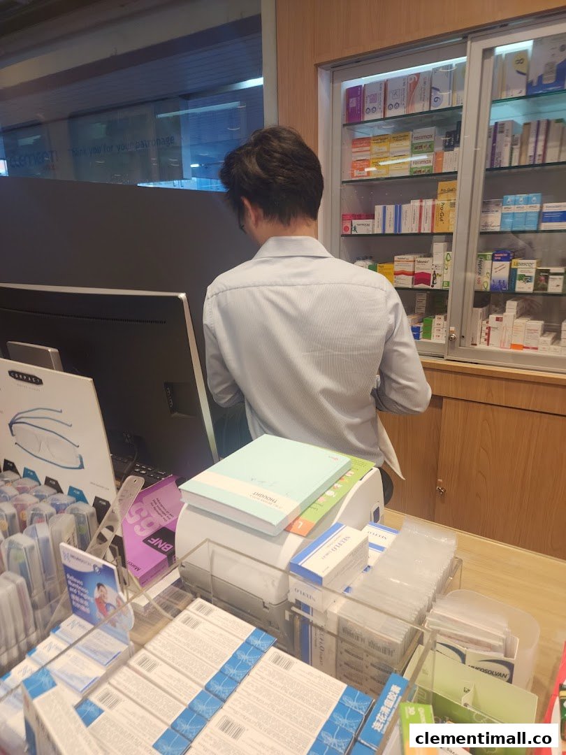 A staff member assists at the Guardian pharmacy counter, surrounded by health and beauty products.