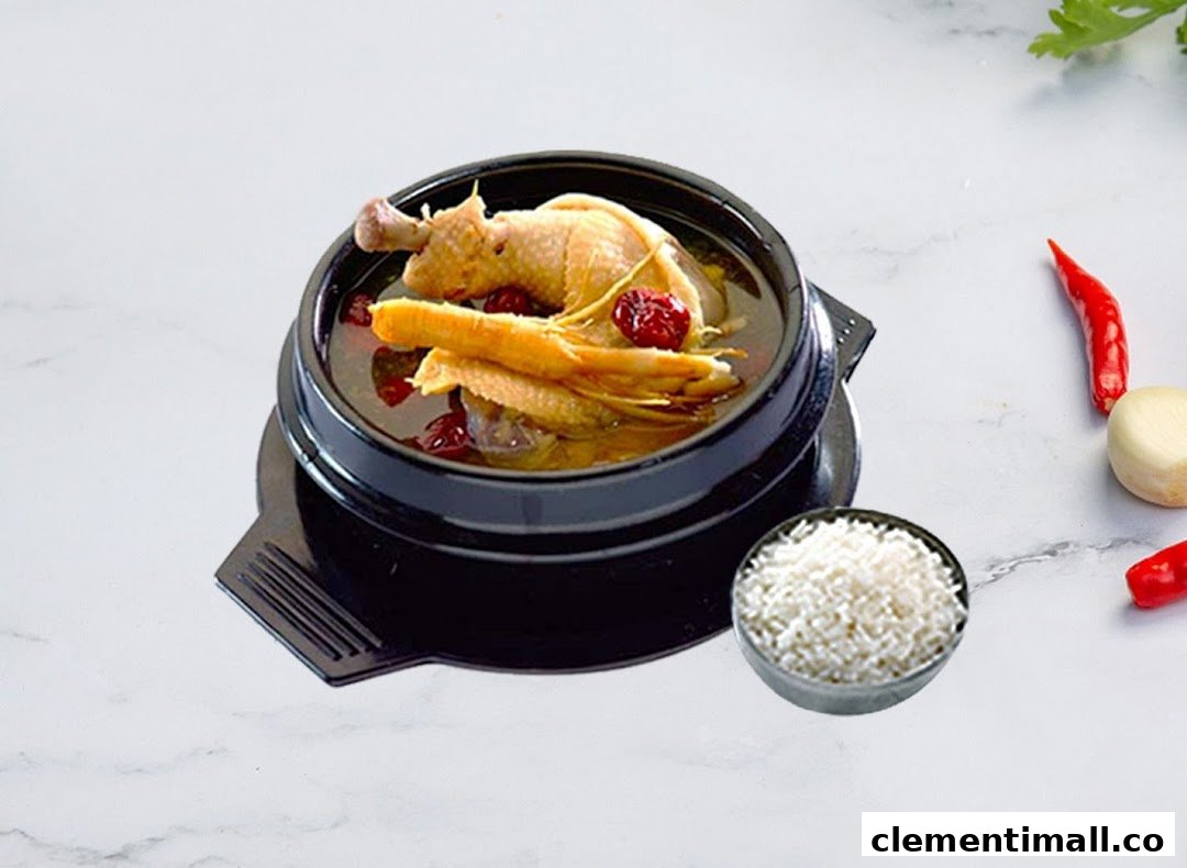 A traditional Korean chicken soup (Samgyetang) served in a black pot with a side of rice.