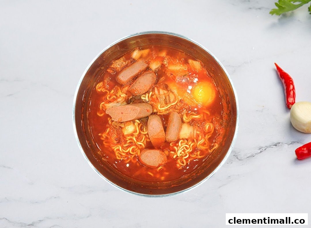 A vibrant bowl of Korean ramen with sausage, kimchi, and a raw egg yolk.